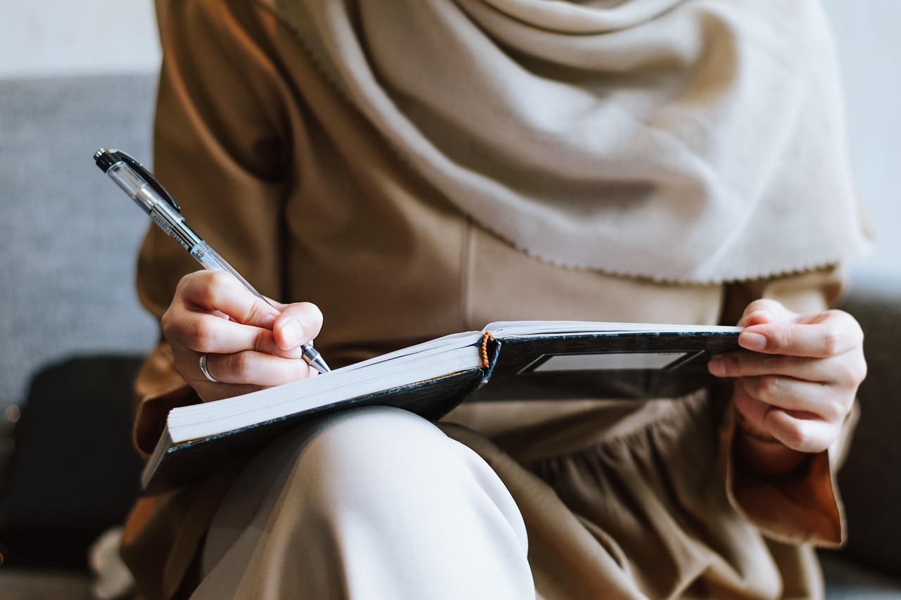 Muslim, woman, writing — The Role of Austin Harris MD in Enhancing Patient Outcomes Through Safer Anesthesia Practices